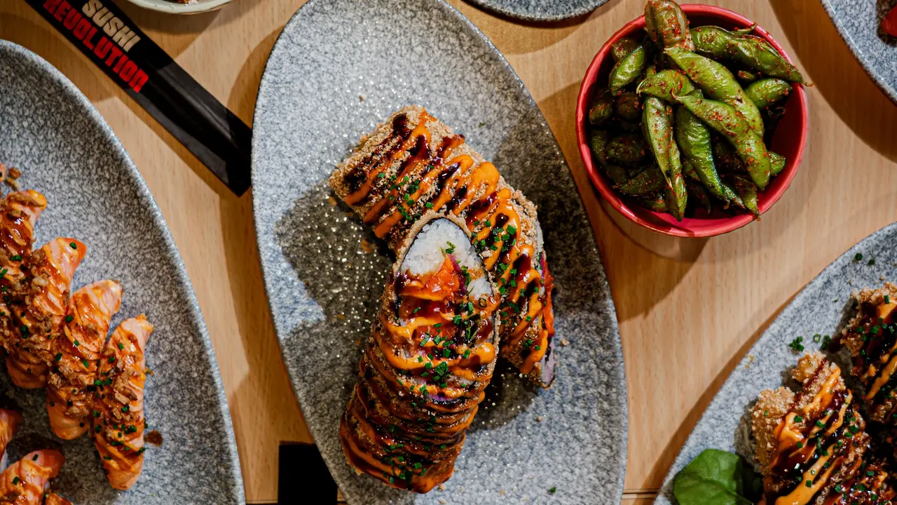 Flatlay med sushi burrito, rullar, edamame och chicken bites på Sushi Revolutions brickor