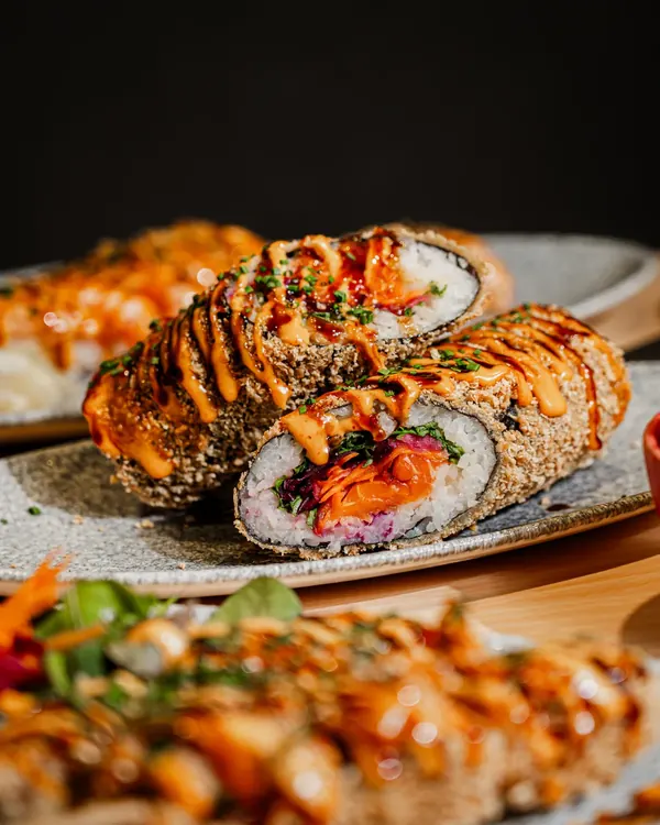 Sushi Burrito delad på mitten med sås och sallad, Sushi Revolutions signaturrätt